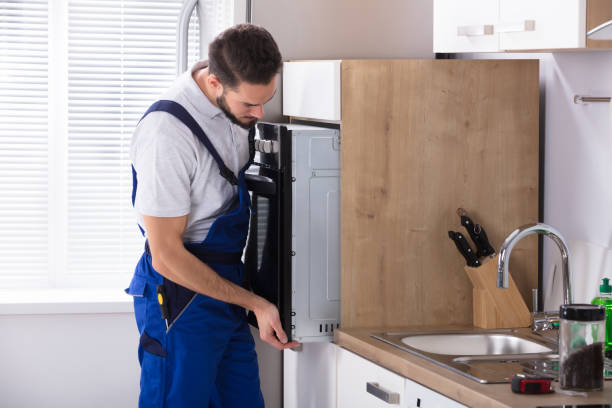 Technician servicing a built-in wall oven in a modern kitchen